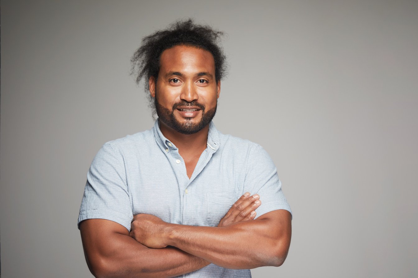 Studio headshot of Australian Aboriginal man on grey background.